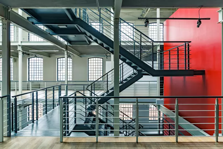 wnętrze budynku z czerwoną ścianą czarnymi metalowymi schodami i balustradą